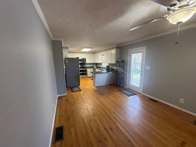 kitchen featuring white cabinets, a textured ceiling, stainless steel appliances, and crown molding