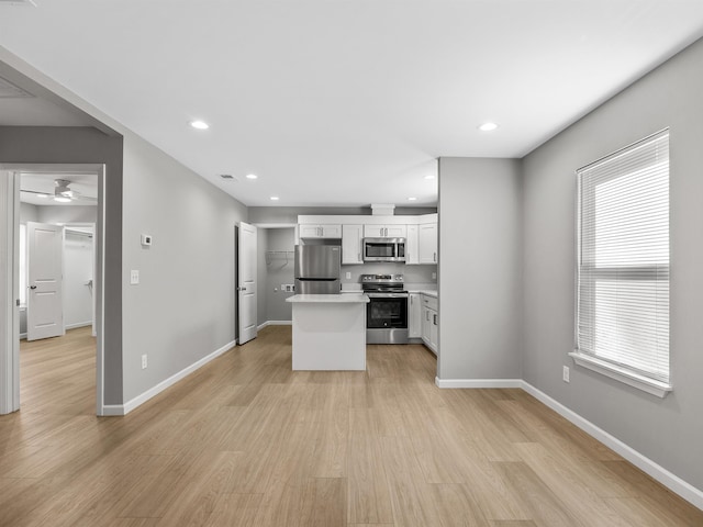 kitchen featuring white cabinets, ceiling fan, light wood-type flooring, appliances with stainless steel finishes, and a kitchen island