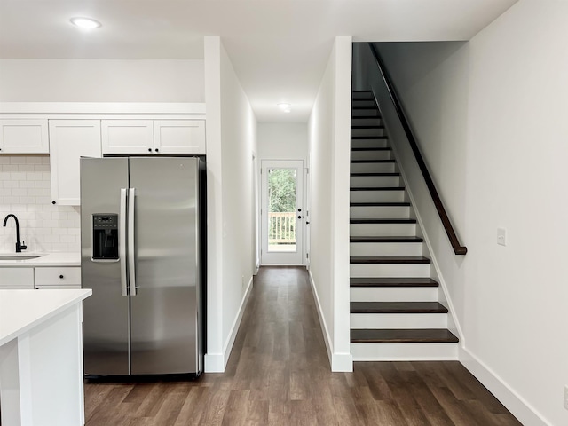 kitchen with decorative backsplash, dark wood-type flooring, sink, stainless steel fridge with ice dispenser, and white cabinetry