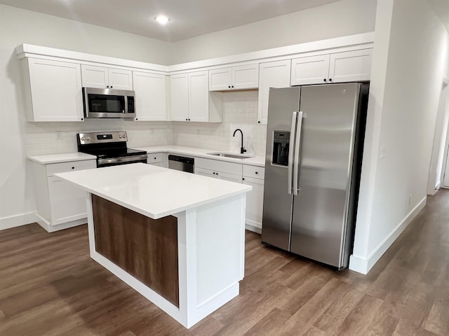 kitchen featuring appliances with stainless steel finishes, dark wood-type flooring, sink, white cabinets, and a kitchen island