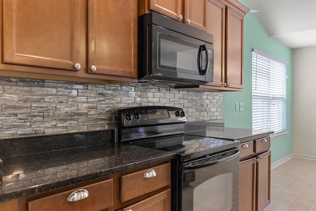 kitchen with dark stone counters, a wealth of natural light, tasteful backsplash, and black appliances