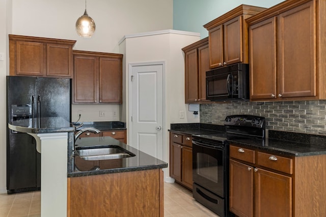 kitchen featuring pendant lighting, black appliances, sink, light tile patterned floors, and an island with sink