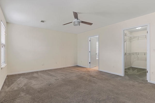 unfurnished bedroom with a closet, a spacious closet, ceiling fan, and light colored carpet