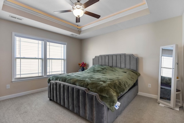 carpeted bedroom featuring ceiling fan, crown molding, and a tray ceiling