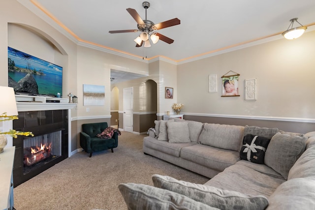 living room featuring carpet, ceiling fan, ornamental molding, and a tiled fireplace