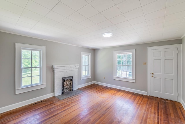 unfurnished living room with plenty of natural light, dark hardwood / wood-style floors, ornamental molding, and a fireplace