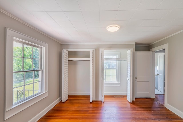 unfurnished bedroom with multiple windows, crown molding, and wood-type flooring