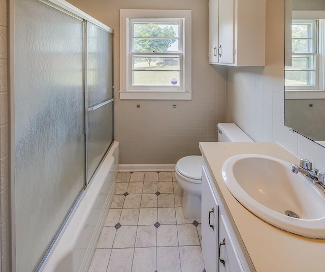 full bathroom featuring tile patterned flooring, enclosed tub / shower combo, toilet, vanity, and tile walls