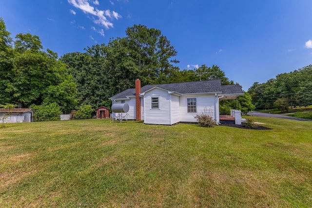 rear view of property with a yard and a storage unit