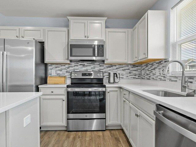 kitchen featuring backsplash, white cabinetry, sink, and appliances with stainless steel finishes