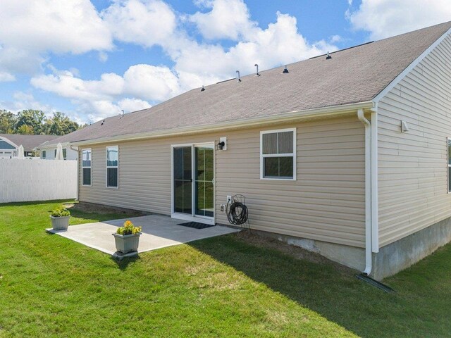 back of property with a lawn and a patio