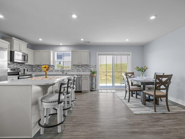 kitchen featuring backsplash, dark hardwood / wood-style floors, a kitchen breakfast bar, and stainless steel appliances