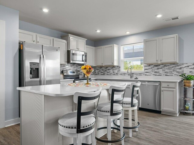 kitchen featuring a center island, white cabinets, a kitchen breakfast bar, sink, and stainless steel appliances