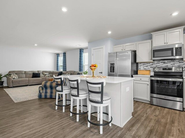 kitchen featuring white cabinetry, stainless steel appliances, a kitchen breakfast bar, backsplash, and a kitchen island