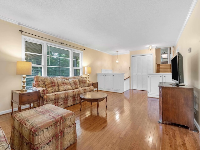 living room featuring crown molding, a textured ceiling, and light wood-type flooring