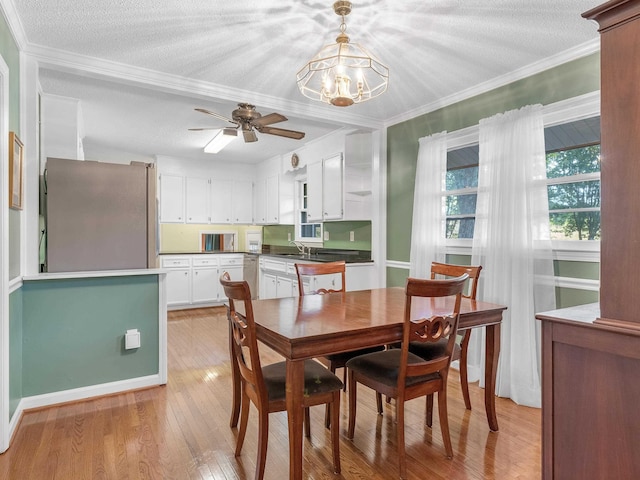 dining room with ceiling fan with notable chandelier, crown molding, sink, light hardwood / wood-style flooring, and a textured ceiling