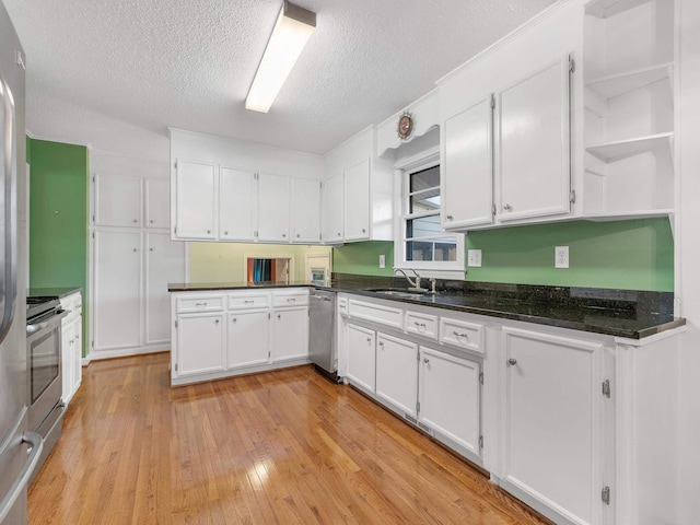 kitchen featuring appliances with stainless steel finishes, a textured ceiling, sink, white cabinets, and light hardwood / wood-style floors