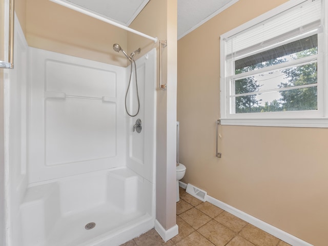 bathroom featuring tile patterned flooring, toilet, and a shower