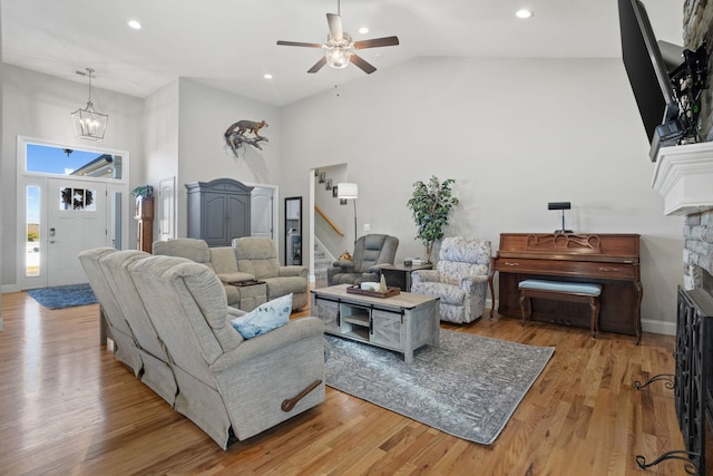 living room with ceiling fan, light hardwood / wood-style floors, a fireplace, and high vaulted ceiling