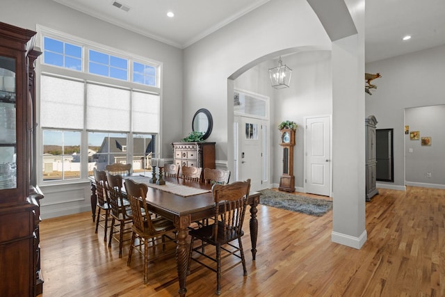 dining room with light wood-type flooring, crown molding, and an inviting chandelier