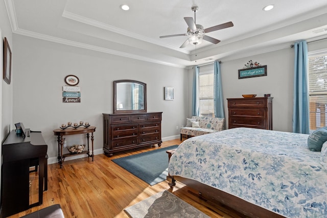 bedroom featuring ceiling fan, light wood-type flooring, crown molding, and a tray ceiling