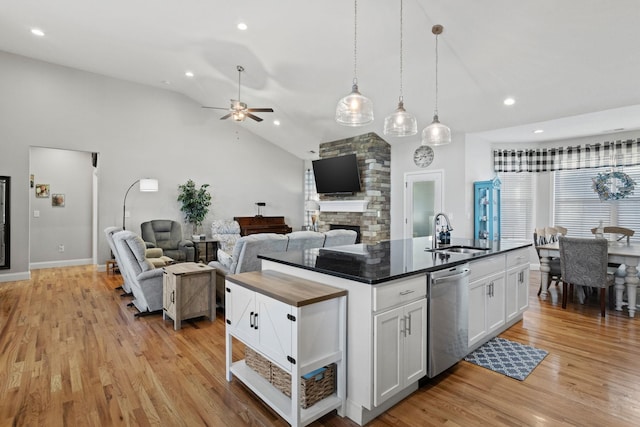 kitchen featuring stainless steel dishwasher, vaulted ceiling, a kitchen island with sink, sink, and white cabinets