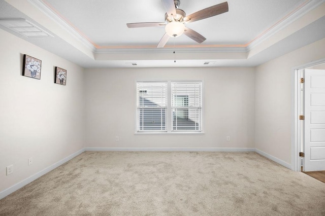 spare room featuring a raised ceiling, light carpet, ceiling fan, and ornamental molding