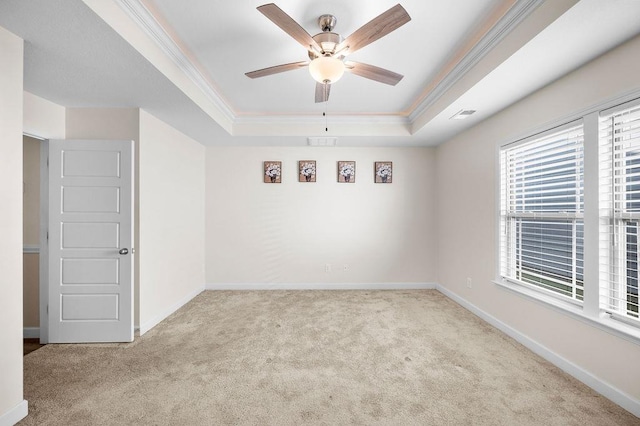 spare room with light colored carpet, ornamental molding, and a tray ceiling