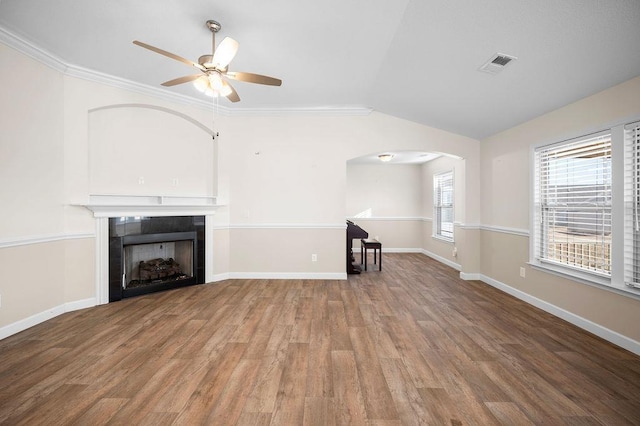 unfurnished living room featuring crown molding, vaulted ceiling, hardwood / wood-style flooring, ceiling fan, and a tiled fireplace