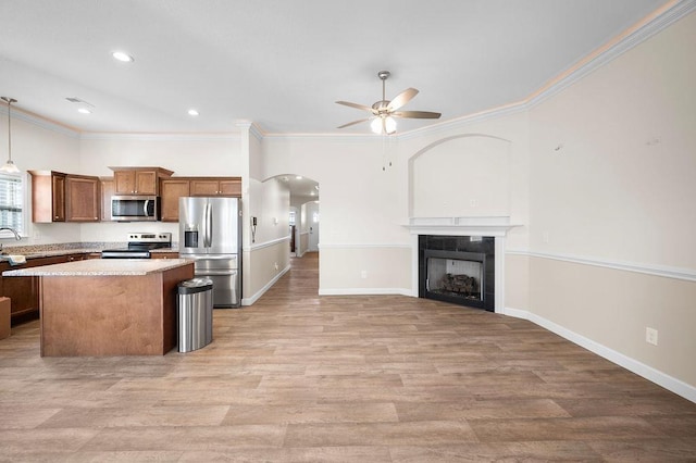 kitchen featuring ceiling fan, stainless steel appliances, light hardwood / wood-style flooring, a kitchen island, and ornamental molding