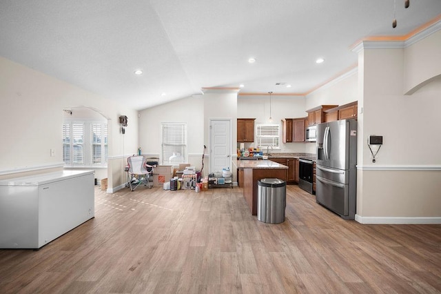 kitchen featuring light stone countertops, appliances with stainless steel finishes, light hardwood / wood-style floors, and a kitchen island