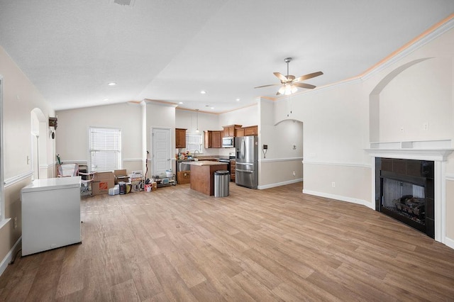 living room featuring ceiling fan, light wood-type flooring, ornamental molding, and a tile fireplace