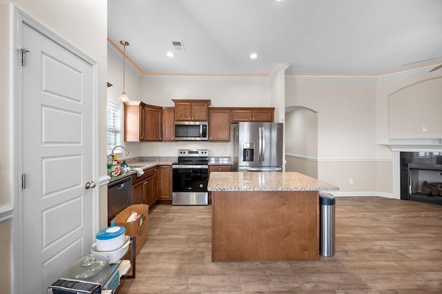 kitchen featuring decorative light fixtures, light stone countertops, appliances with stainless steel finishes, and light hardwood / wood-style flooring