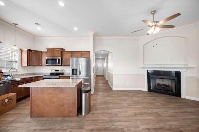 kitchen with sink, ceiling fan, decorative light fixtures, stainless steel appliances, and a tiled fireplace