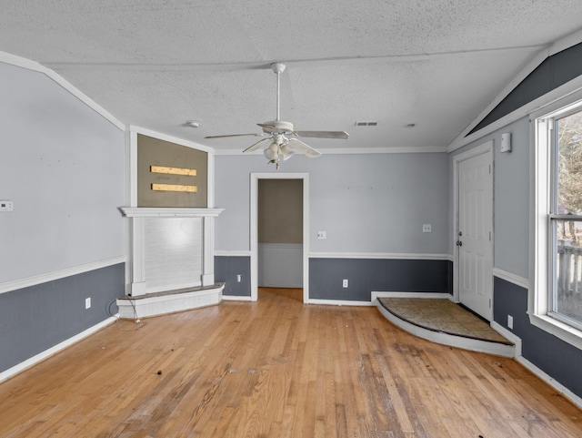 unfurnished living room featuring a healthy amount of sunlight, ceiling fan, light hardwood / wood-style floors, and vaulted ceiling