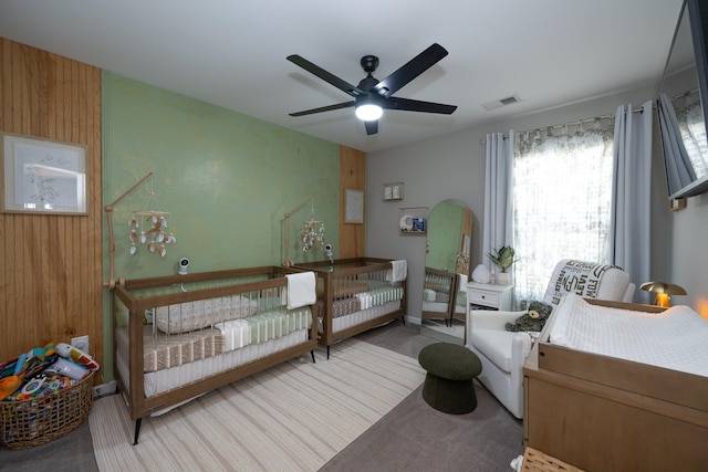 carpeted bedroom with ceiling fan and wooden walls