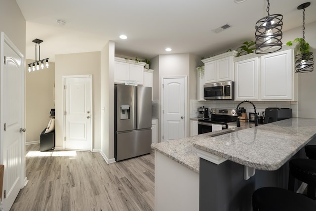 kitchen featuring white cabinets, decorative light fixtures, stainless steel appliances, and kitchen peninsula