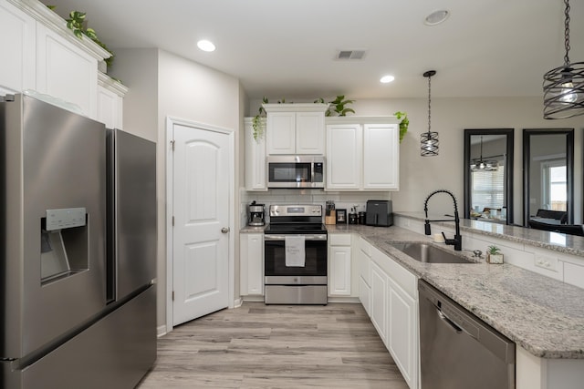 kitchen featuring sink, white cabinetry, hanging light fixtures, and appliances with stainless steel finishes