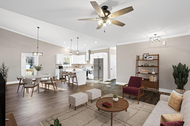 living room featuring ceiling fan with notable chandelier, dark hardwood / wood-style flooring, and ornamental molding