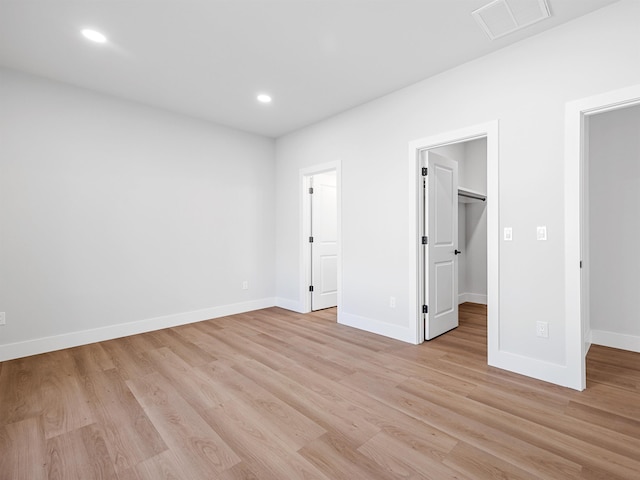 unfurnished bedroom featuring light wood-type flooring, a walk in closet, and a closet