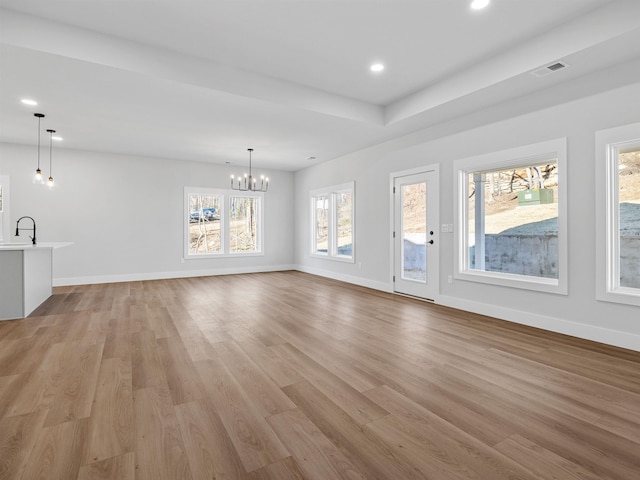 unfurnished living room with light hardwood / wood-style flooring, a notable chandelier, and sink