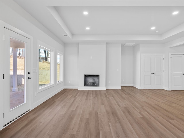 unfurnished living room with a raised ceiling and light hardwood / wood-style flooring