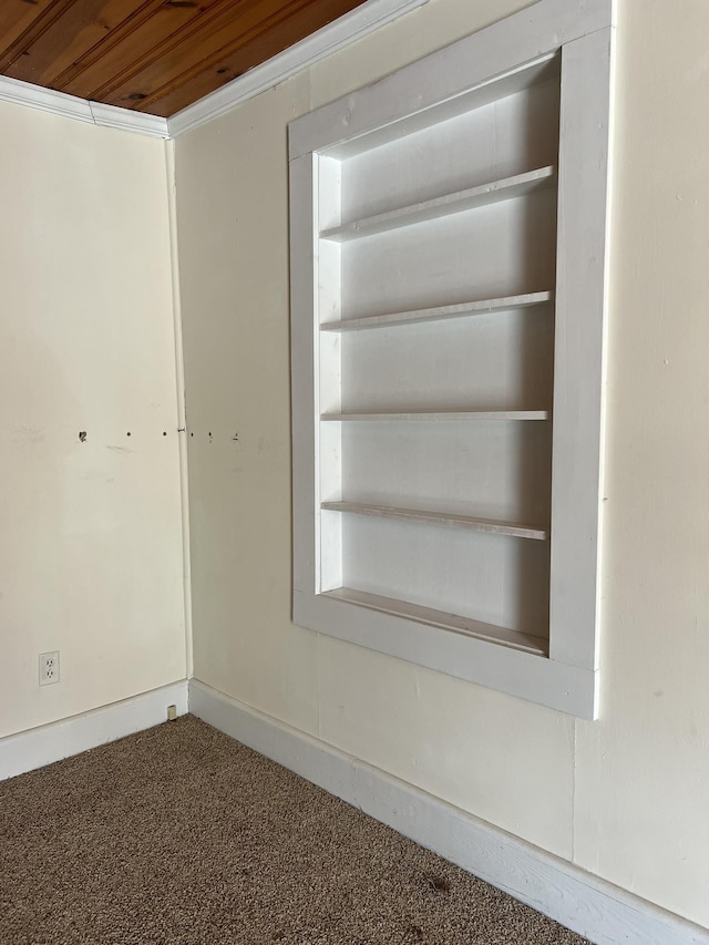 interior space with built in shelves, crown molding, carpet, and wood ceiling