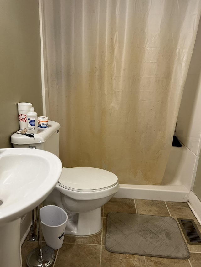 bathroom featuring a shower with curtain and toilet