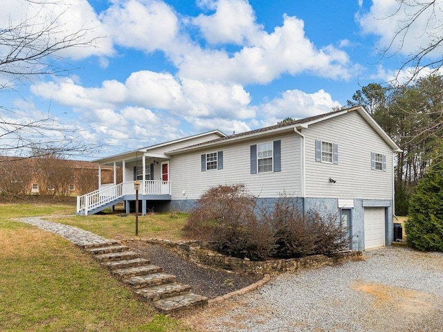 exterior space featuring a porch, a garage, and a lawn