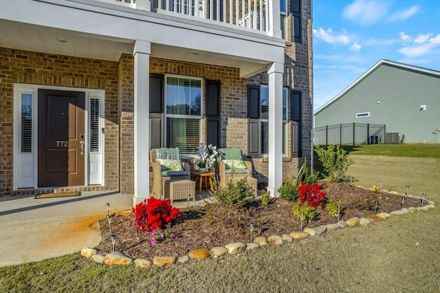 view of exterior entry featuring a lawn and a balcony