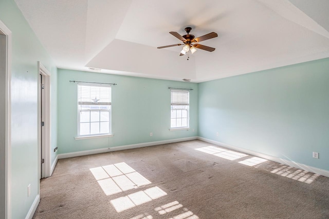 spare room with a raised ceiling, ceiling fan, light colored carpet, and a healthy amount of sunlight