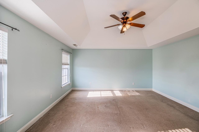 unfurnished room with a raised ceiling, ceiling fan, and carpet