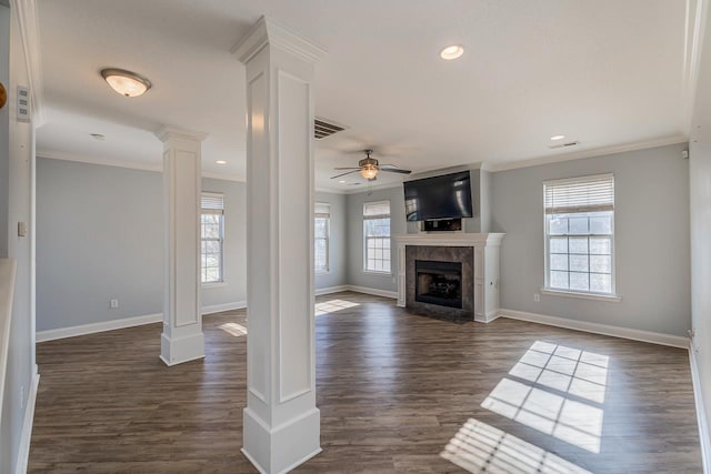 unfurnished living room with decorative columns, ornamental molding, ceiling fan, dark wood-type flooring, and a tile fireplace