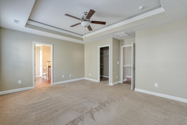 unfurnished bedroom featuring a tray ceiling, ceiling fan, and crown molding